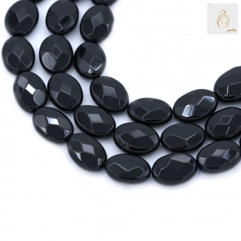 Black agate faceted oval beads 10x14mm scattered display showing glossy surface and geometric faceted cuts for jewelry making