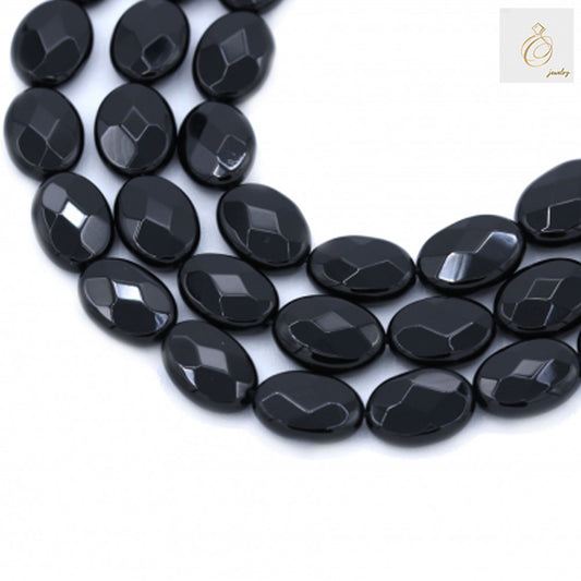 Black agate faceted oval beads 10x14mm scattered display showing glossy surface and geometric faceted cuts for jewelry making