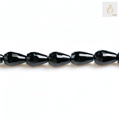 Close-up view of black agate faceted teardrop beads in a single strand highlighting the precise faceting and glossy surface