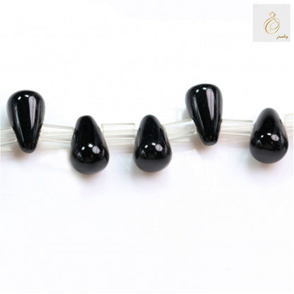 Close-up of five black agate teardrop beads 5x8mm showing glossy finish and uniform shape
