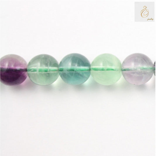 Natural fluorite round beads 10mm diameter arranged on white background showing translucent purple and green color
