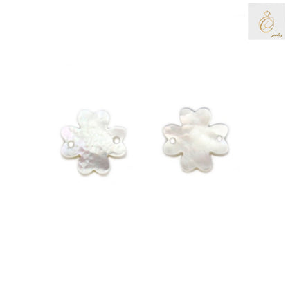 Close-up view of white mother-of-pearl clover charms showing natural iridescent surface texture