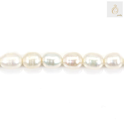 Close-up view of white freshwater cultured pearls showing lustrous surface and oval shape, 6-7mm size